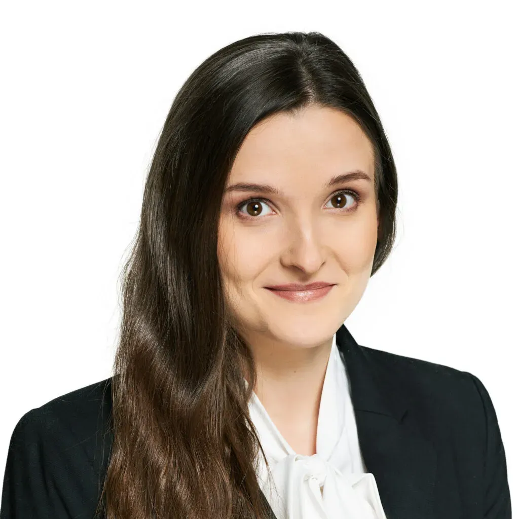 Adwokatka kancelarii KRK z długimi, ciemnobrązowymi włosami, w czarnym żakiecie i białej bluzce z wiązaniem – profesjonalny portret do sekcji Zespół