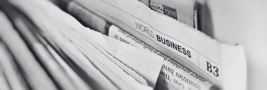 Czarno-białe zdjęcie gazet z nagłówkiem „World Business” – ilustracja do sekcji aktualności kancelarii KRK.