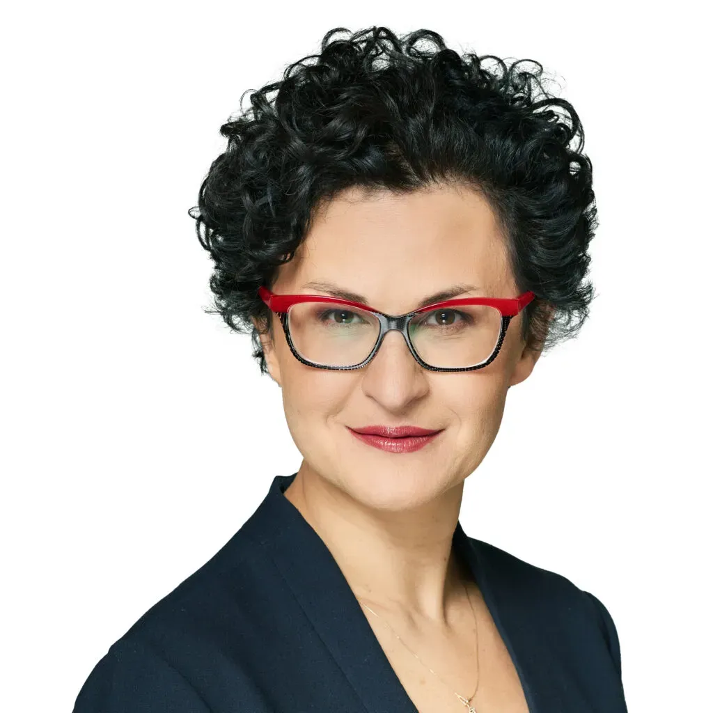 Wspólniczka, adwokatka kancelarii KRK w okularach z czerwono-czarną oprawą, z krótkimi ciemnymi kręconymi włosami, w granatowym żakiecie – profesjonalny portret do sekcji Zespół